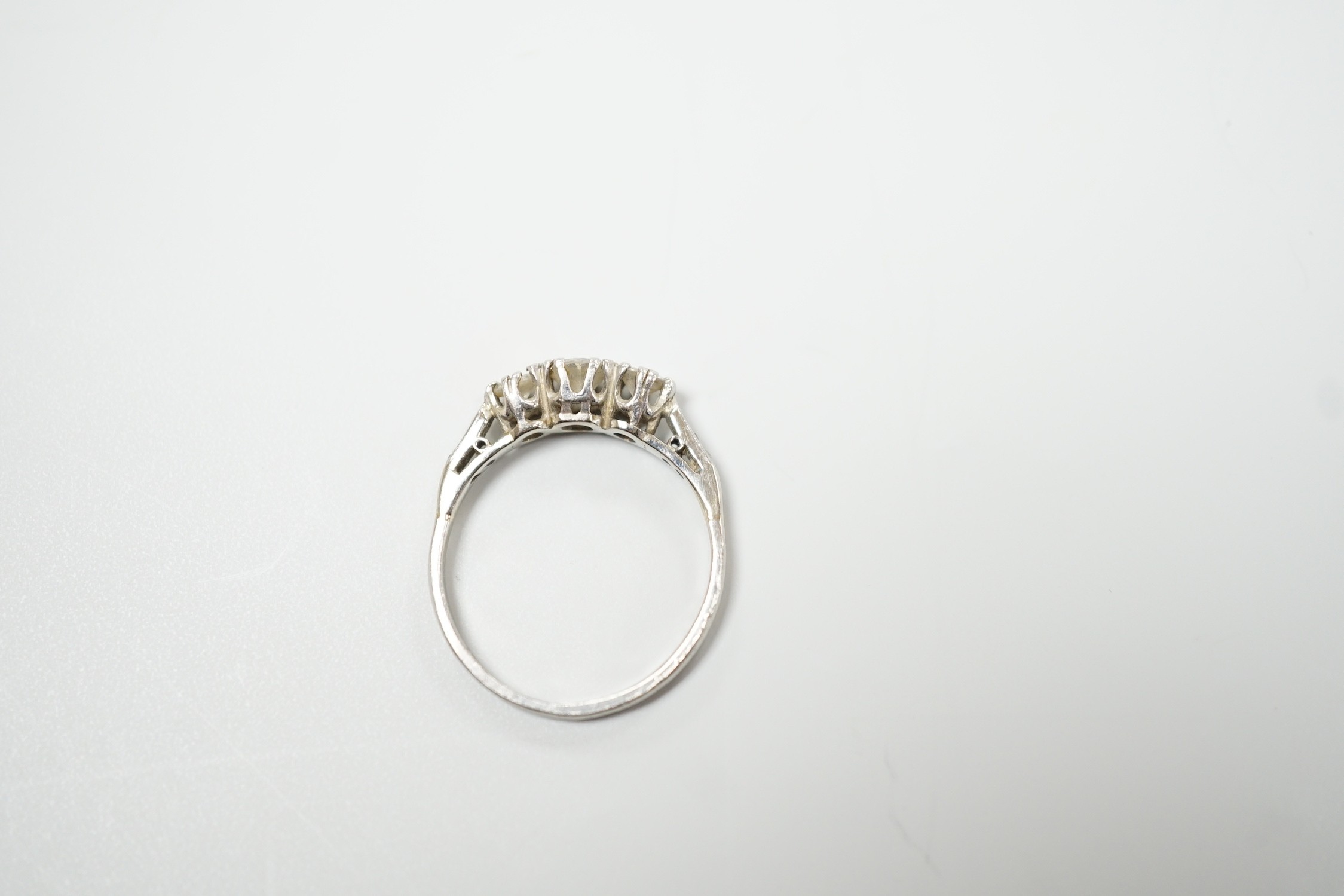 A white metal, stamped plat and three stone diamond set ring, size M/N, gross weight 2.8 grams, with diamond chip set shoulders.